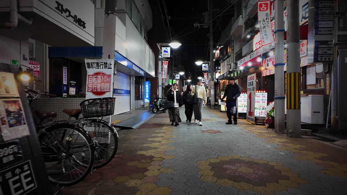 Izakayas lining the Shoten-dori shopping street at night, with touts standing outside