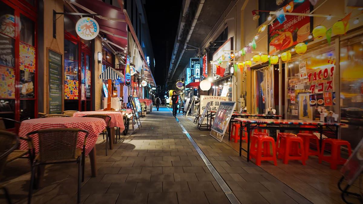 A restaurant with tables and chairs set out on the footpath at night