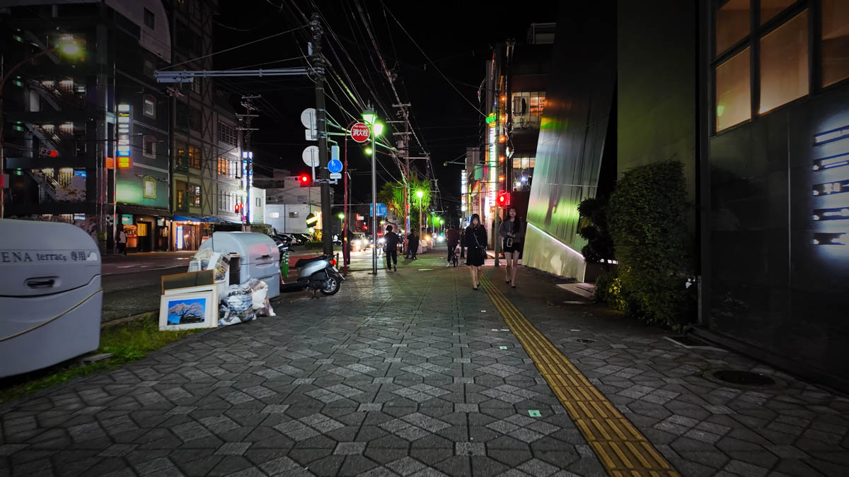 A woman in a flashy outfit walking through the entertainment district at night