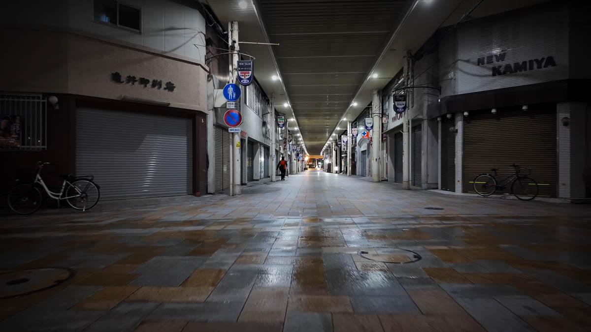 Shuttered shops lining the arcade at night, the street completely still