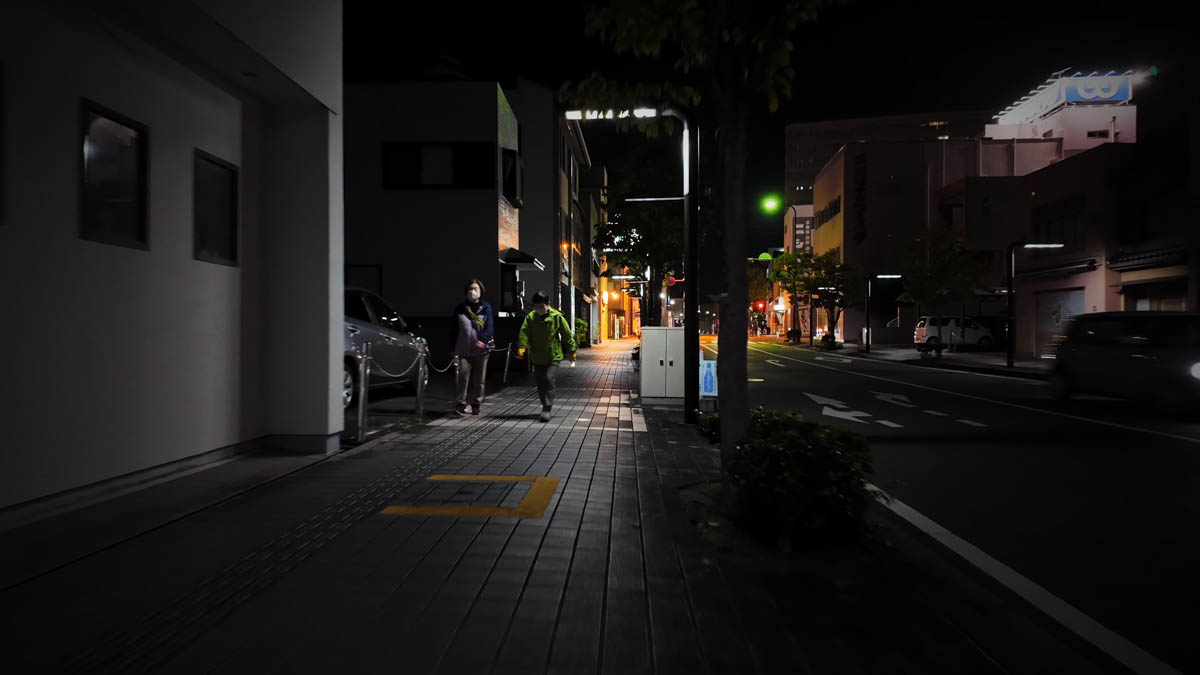 Two women walking at night with a torch, chatting as they go