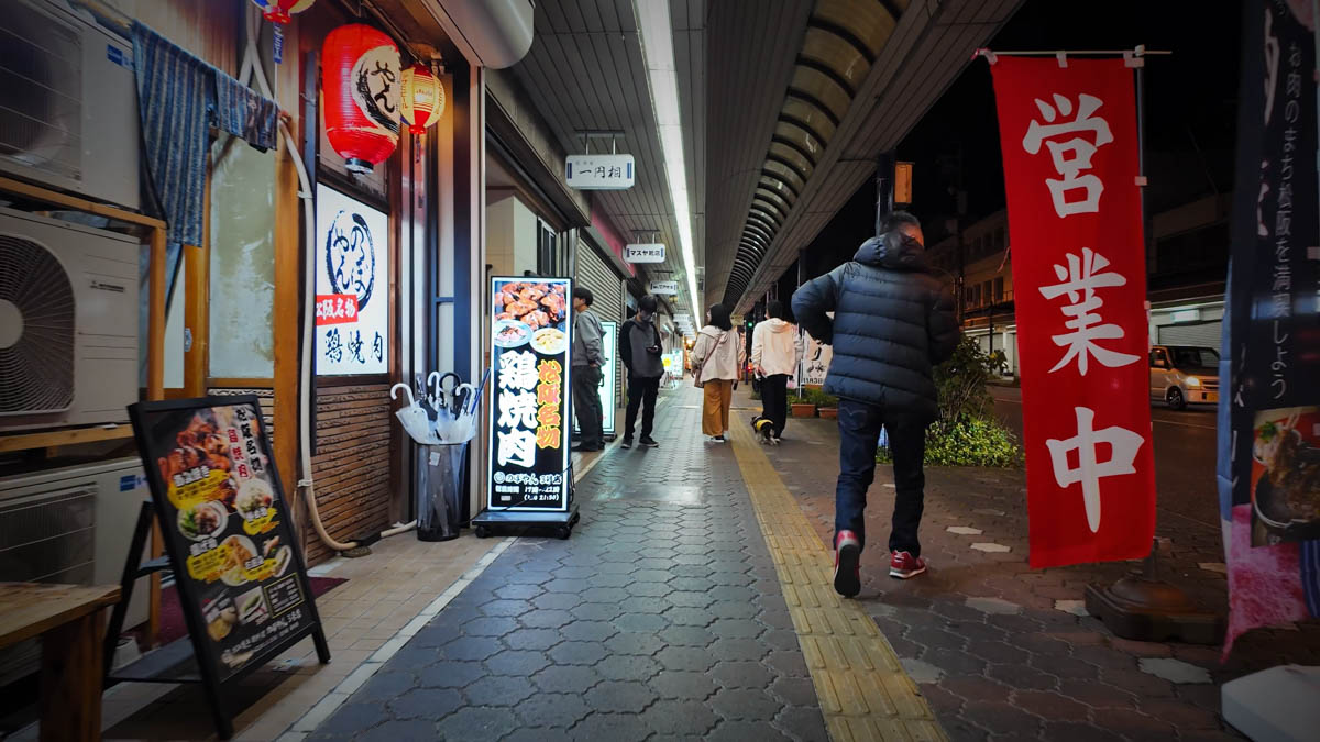 Night view of the shopping street near Matsusaka Station, with signs for grilled chicken visible