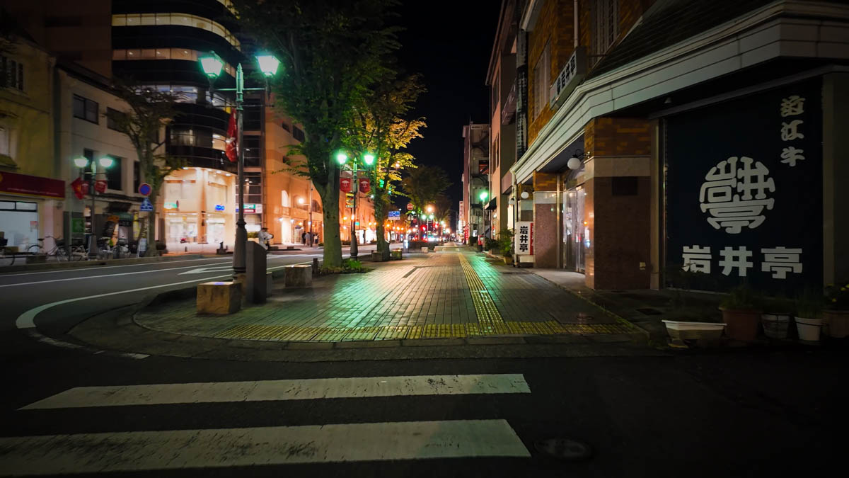The bright, well-lit station front street, Al Plaza Yokaichi visible on the left