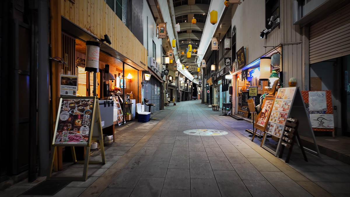 A mix of shuttered stores and stylish open shopfronts along the Honmachi arcade