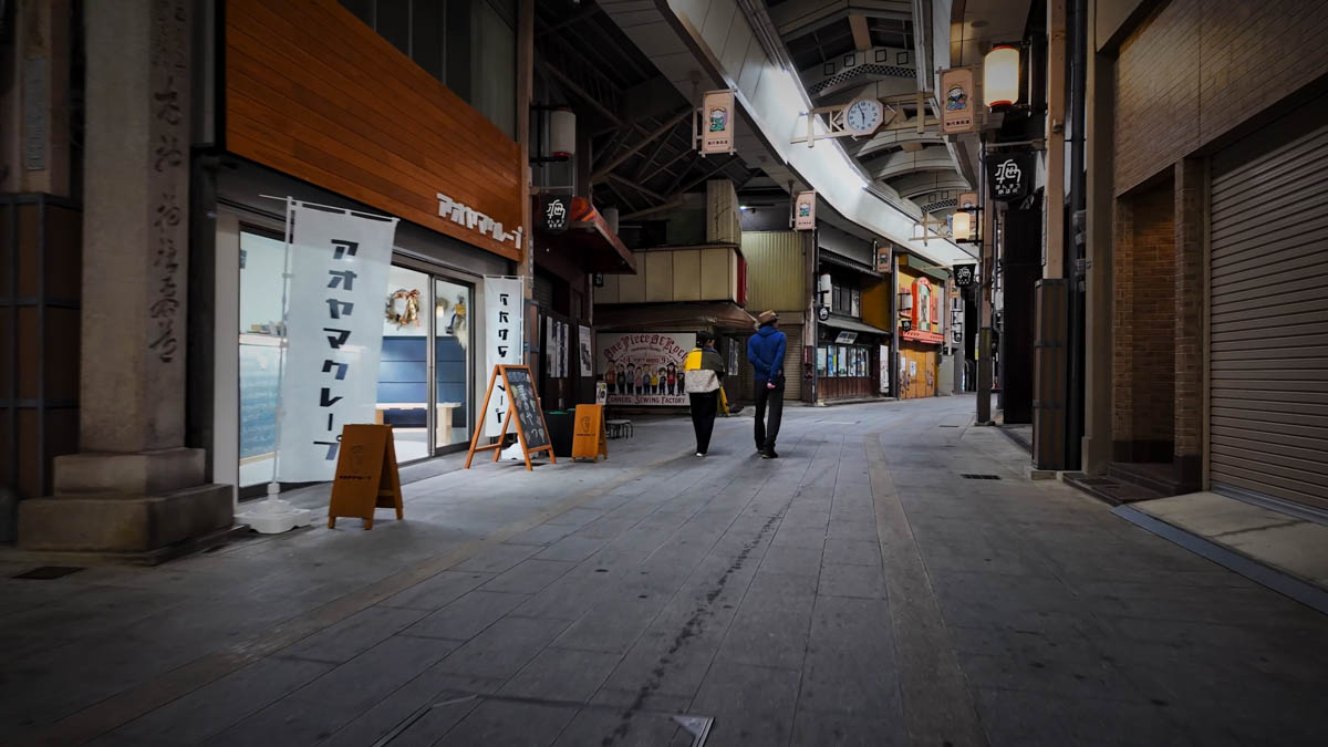A stylish crêpe shop on the arcade street, its white exterior glowing at night