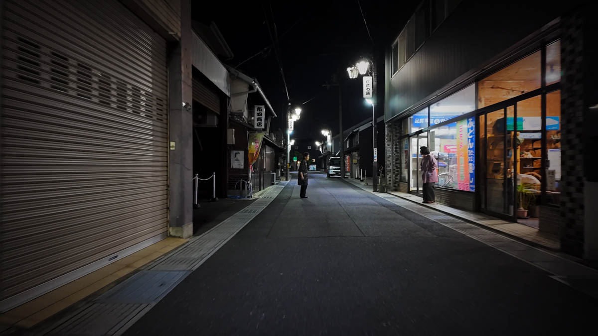 Residents chatting outside on a laneway lined with weathered old buildings