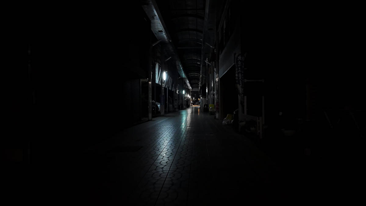 A completely dark narrow lane branching off the arcade