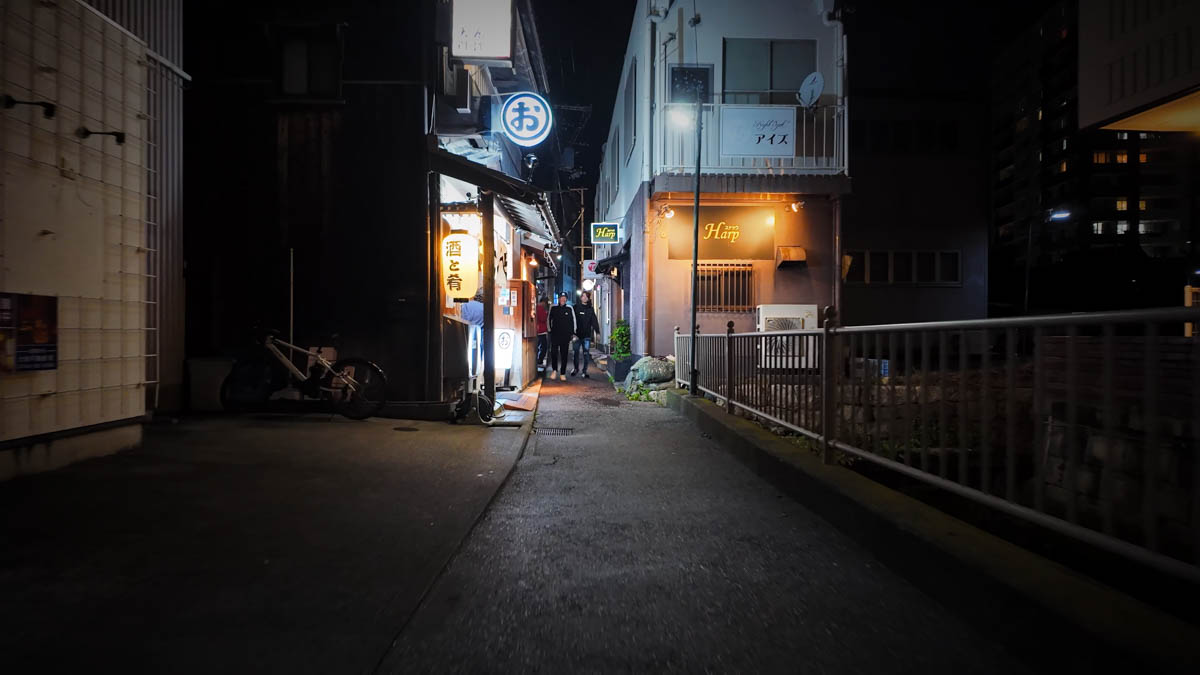 A narrow laneway with an old converted house operating as an izakaya, warm light seeping out