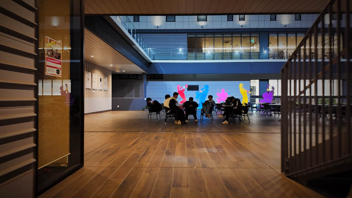 Students gathered in the courtyard-like space on the ground floor of the complex, all looking at their phones