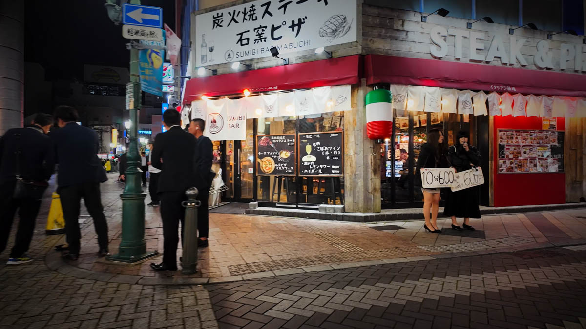 10分600円と書かれたシートを持つガールズバーの女の子たち