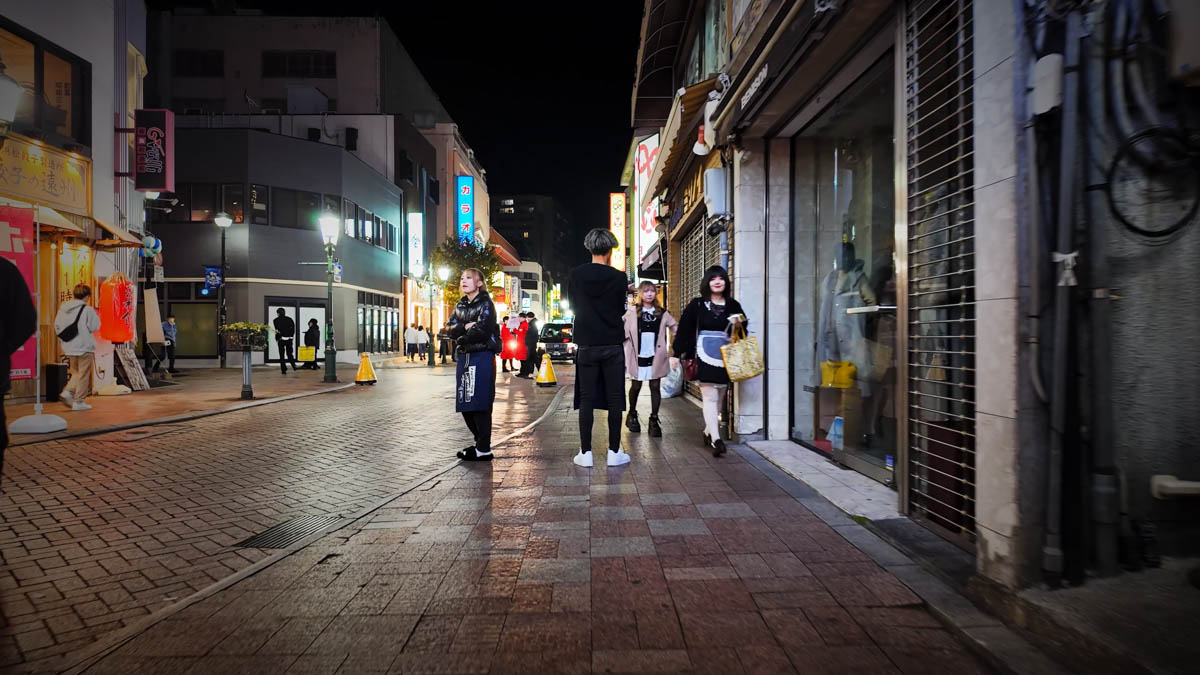 有楽街の通り。居酒屋やバーの客引きが立つ