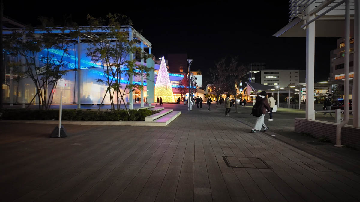 The station plaza at night, still busy with people passing through