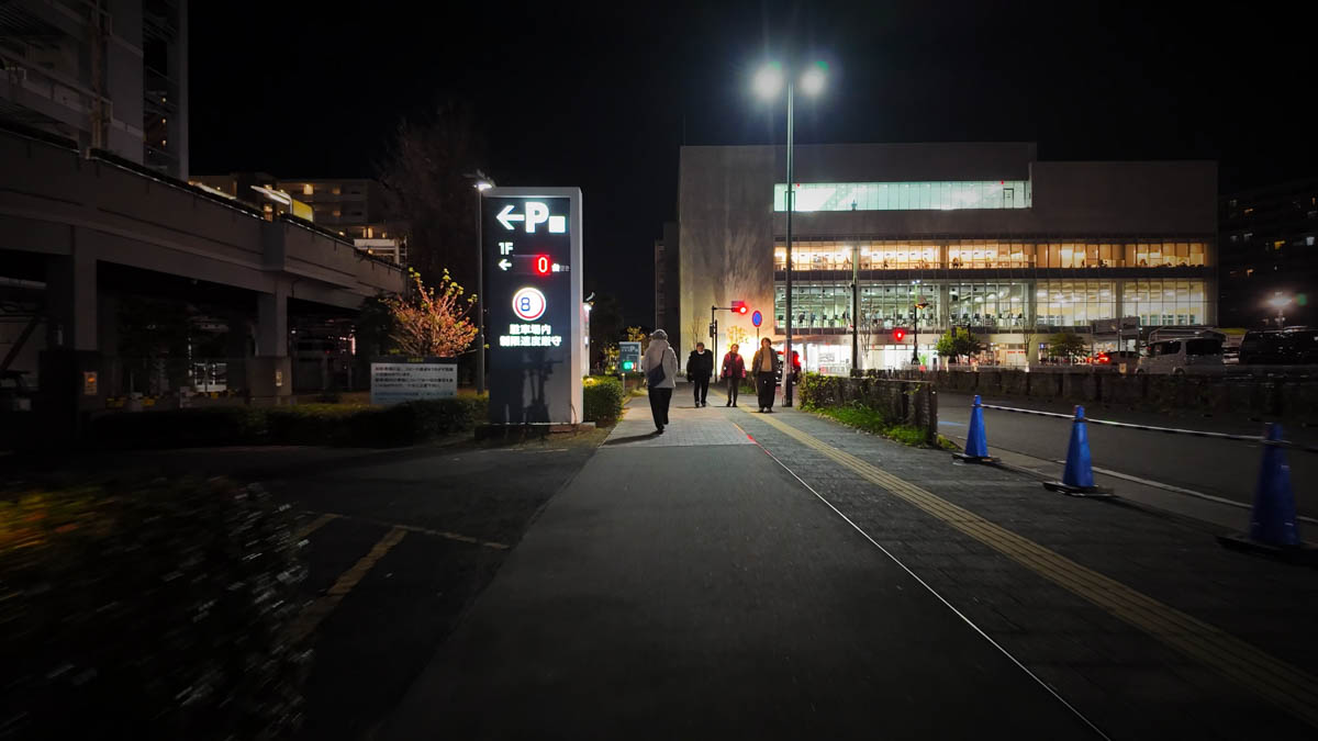 A building housing a large fitness gym on the left side of the street