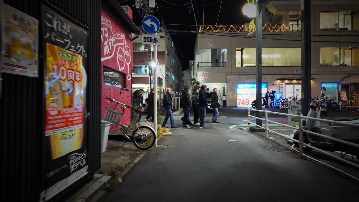 居酒屋の前で盛り上がるグループの男性たち