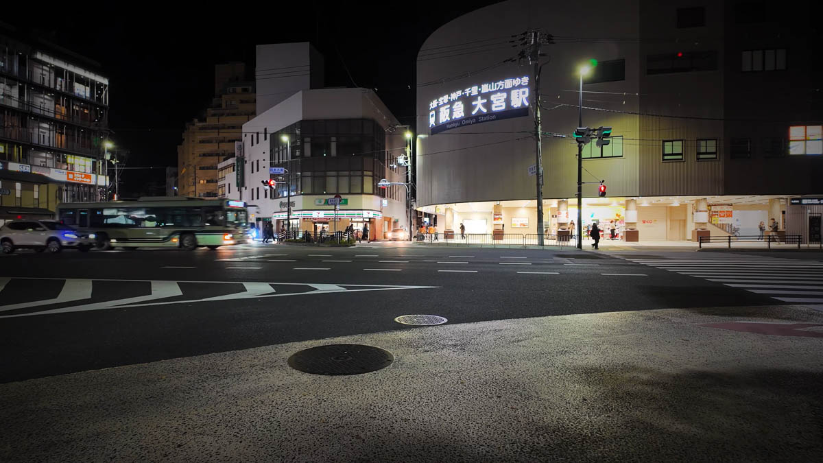 Shijo-Omiya intersection at night, with the entrance to Hankyu Omiya Station and a bus passing by