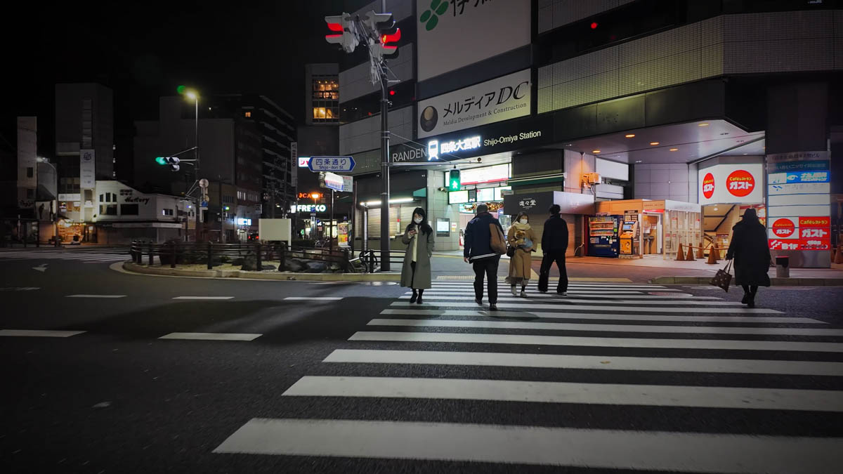 Randen Shijo-Omiya Station at night, with people crossing in front of the station entrance