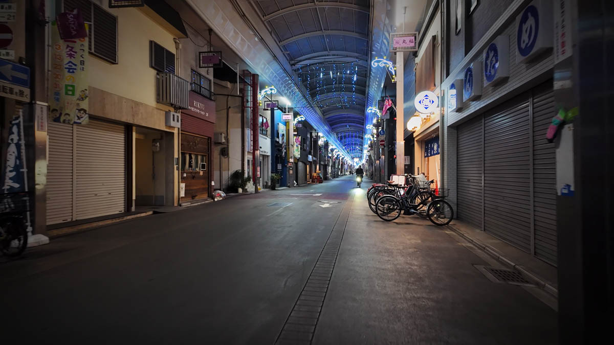 A covered shopping arcade near Omiya Station, with blue-white lights and shuttered shops