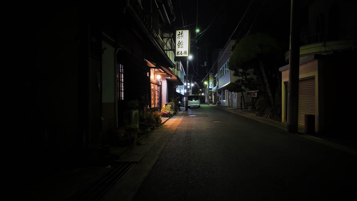 Ryokan Otafuku on a dark night street, with its sign and entrance light standing out in the shadows
