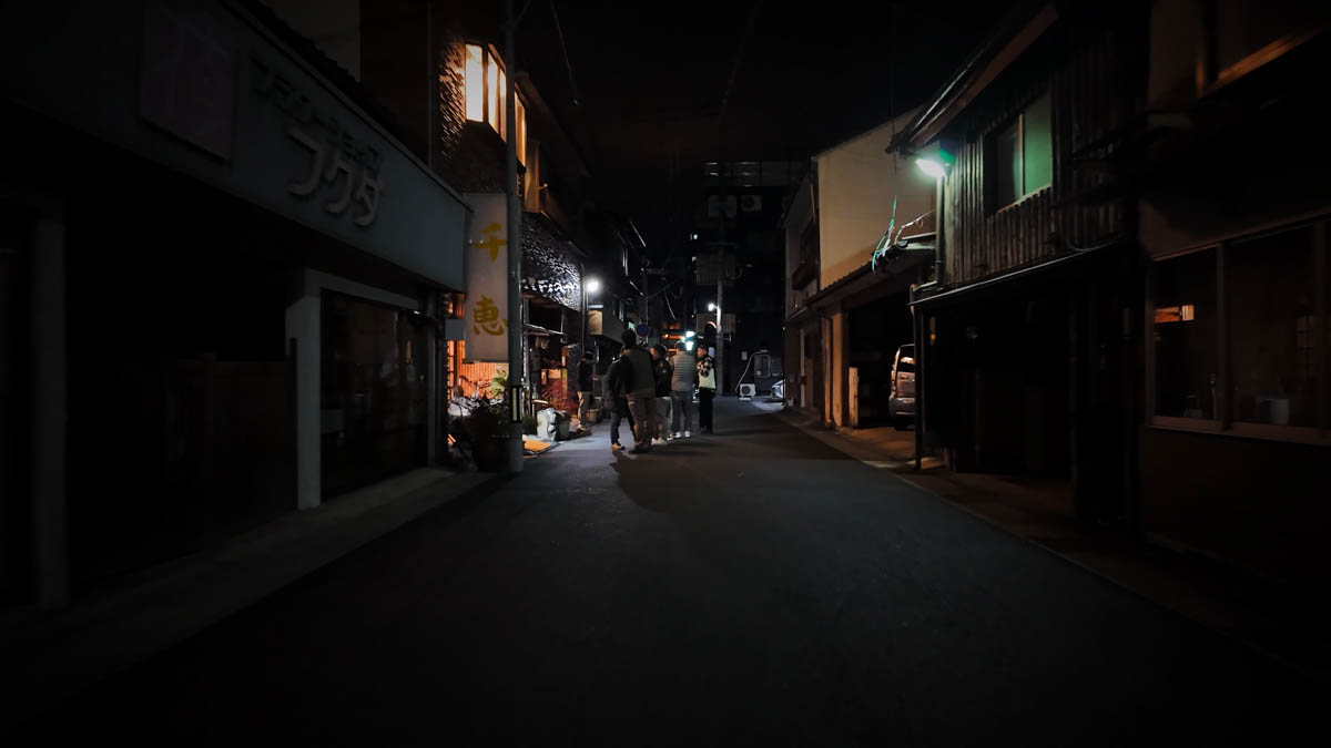 A restaurant street in Tsuyama, with people gathered near the sign for the yakiniku restaurant Chie