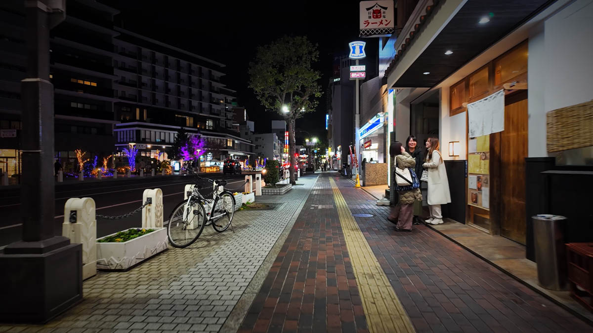 A night street in Kurashiki, with illuminated roadside trees and restaurant lights