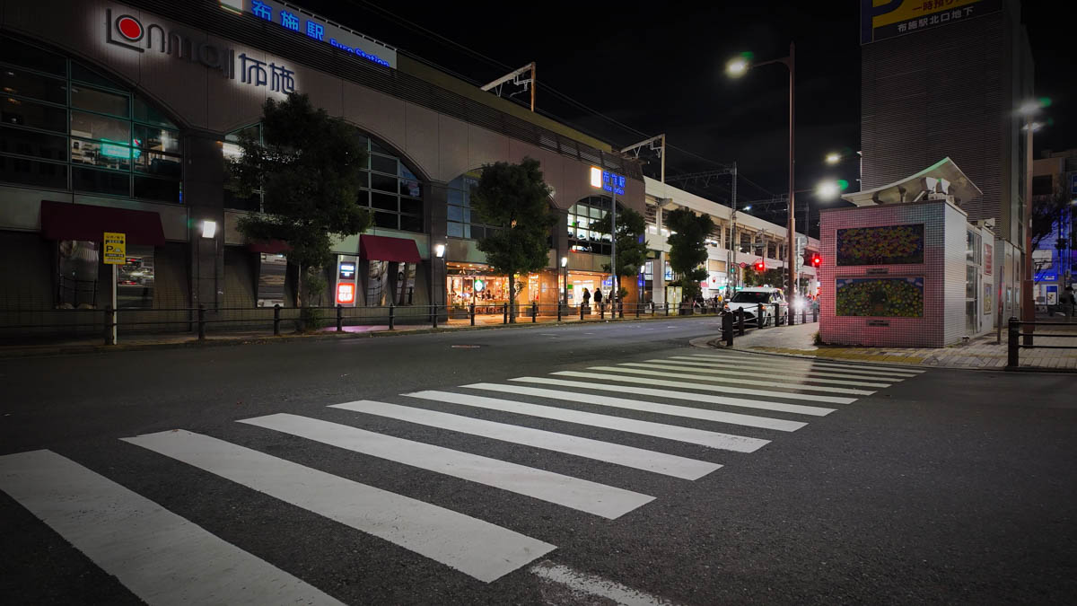 Kintetsu Fuse Station at night, with the station building lights, a crosswalk, and road in front