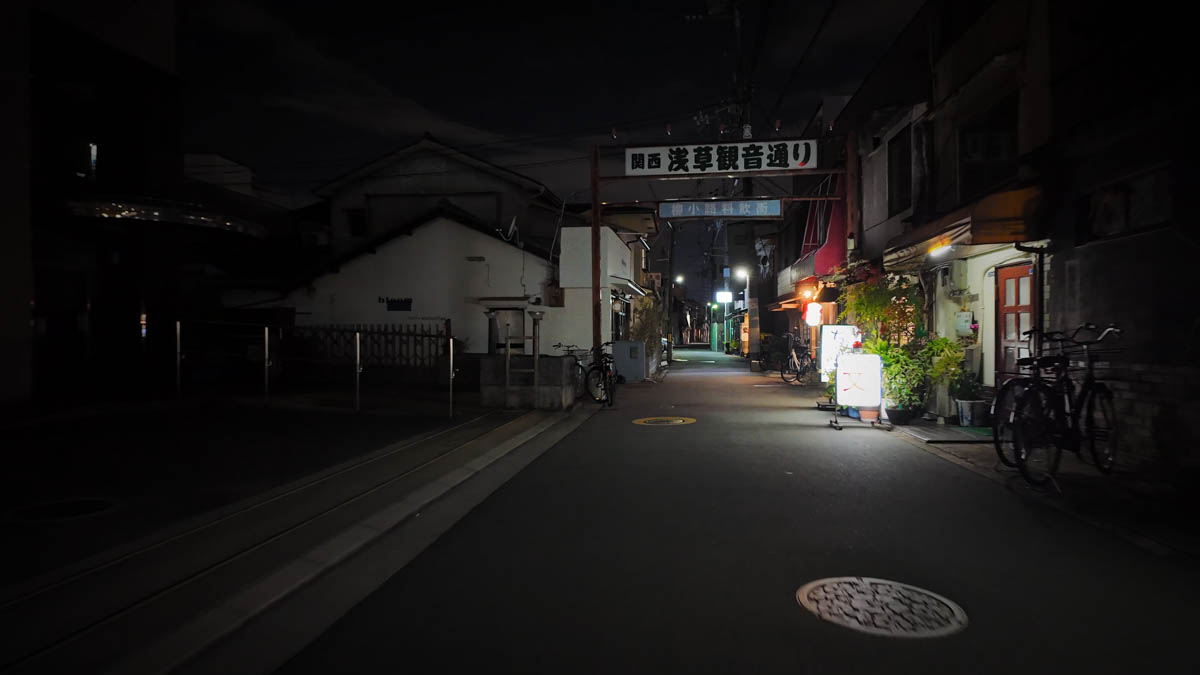 The entrance to Kansai Asakusa Kannon-dori, with restaurant lights visible deep inside the dark street