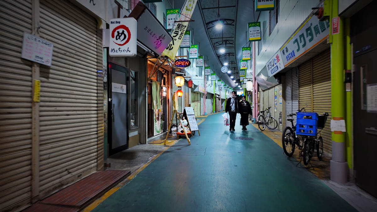 Inside Brando-ri Fuse arcade, with restaurant signs and shuttered shops, and pedestrians moving through