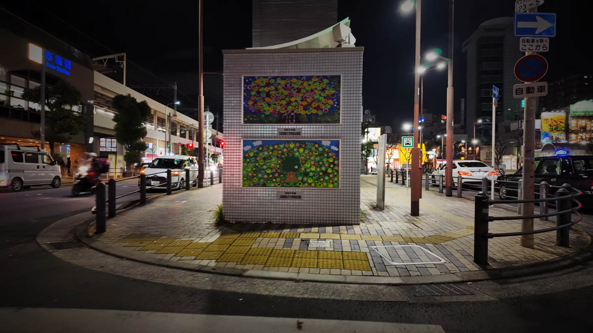 A wall decoration on the sidewalk in front of Fuse Station, with lights from the station and arcade visible on either side
