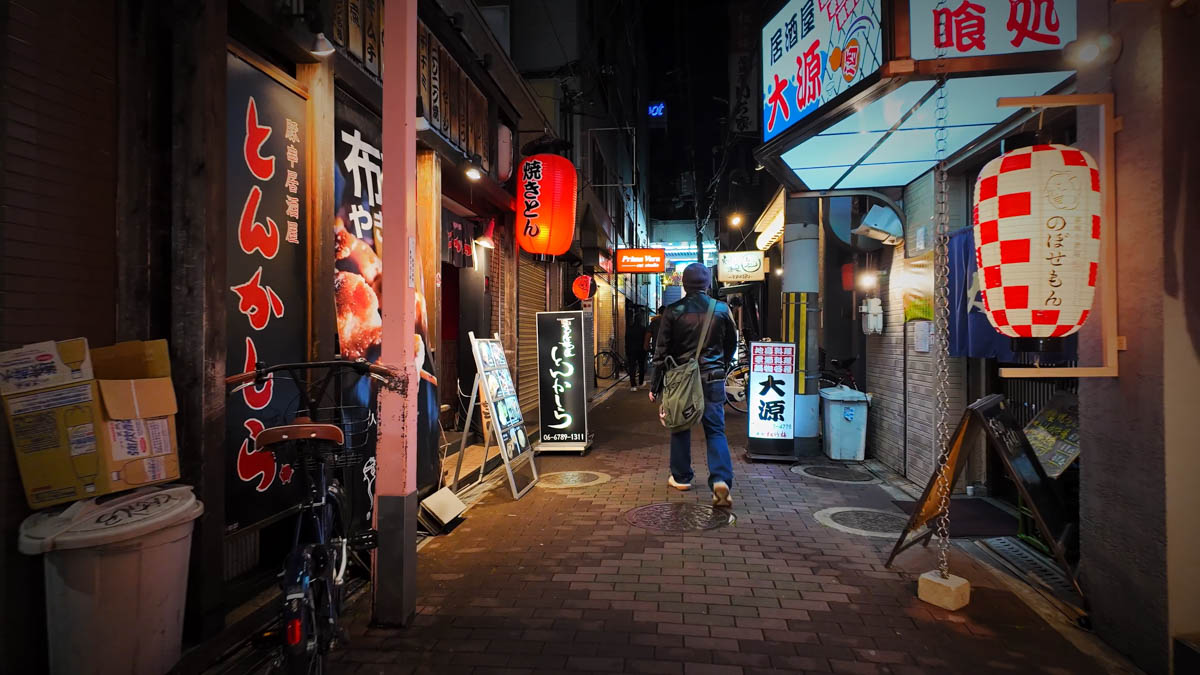 An alley near Fuse Station lined with restaurants, with yakiton shop and izakaya signs and red lanterns glowing