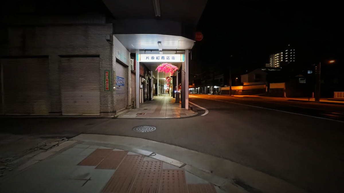 The entrance to Katahara-machi Shopping Street, decorated with pink lanterns and a hanging sign bearing the street's name