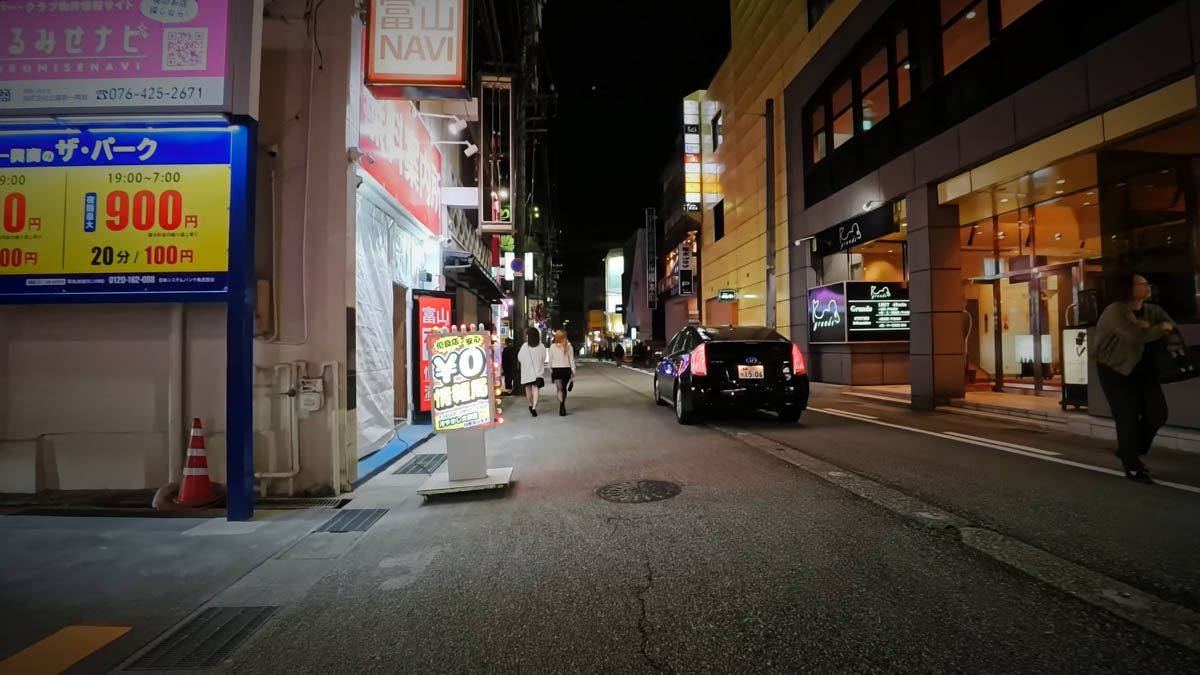 富山駅近くの細い通り。駐車場やホテル、飲食店の看板が見える