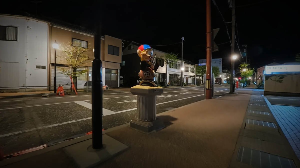 夜の氷見駅前通り（怪物くんストリート）。台座に乗った怪物くんの像と、シャッターの閉まった商店が並ぶ