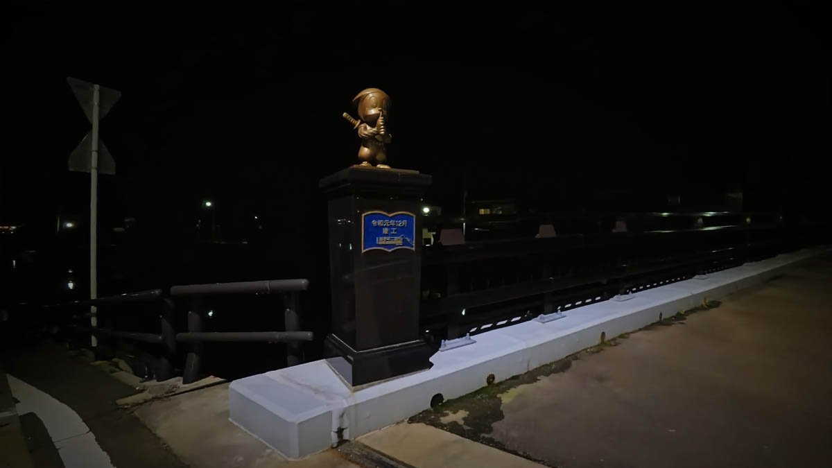 夜の北の橋の欄干に置かれた忍者ハットリくんの銅像。台座に「令和元年12月竣工」の文字がある
