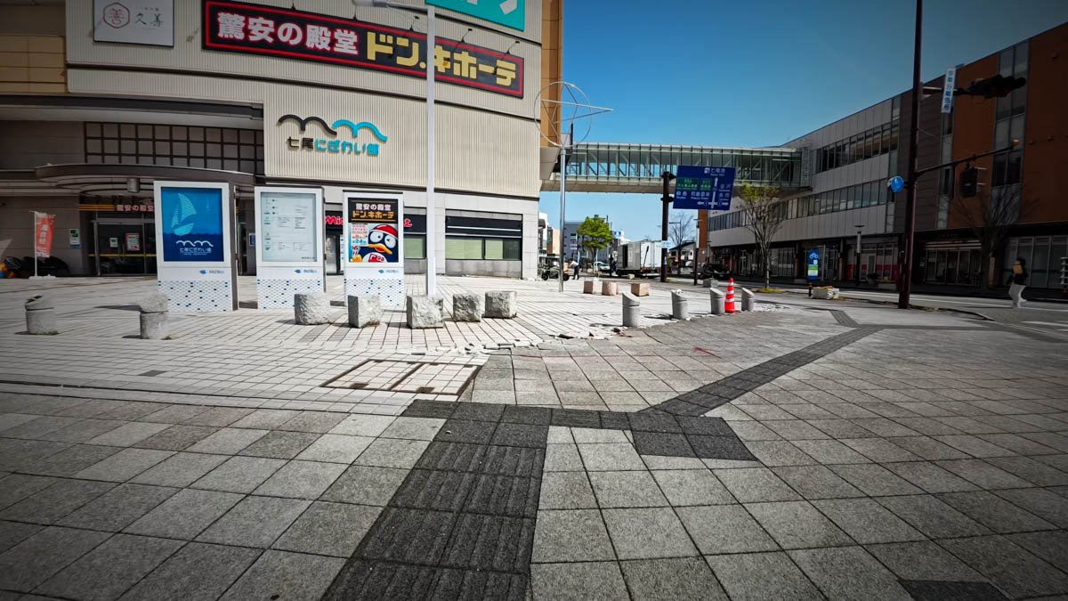 七尾駅前広場 七尾にぎわい館 七尾駅前広場。「七尾にぎわい館」の建物にドン・キホーテの看板が見え、広場の石畳には地震による亀裂や陥没の跡が残る