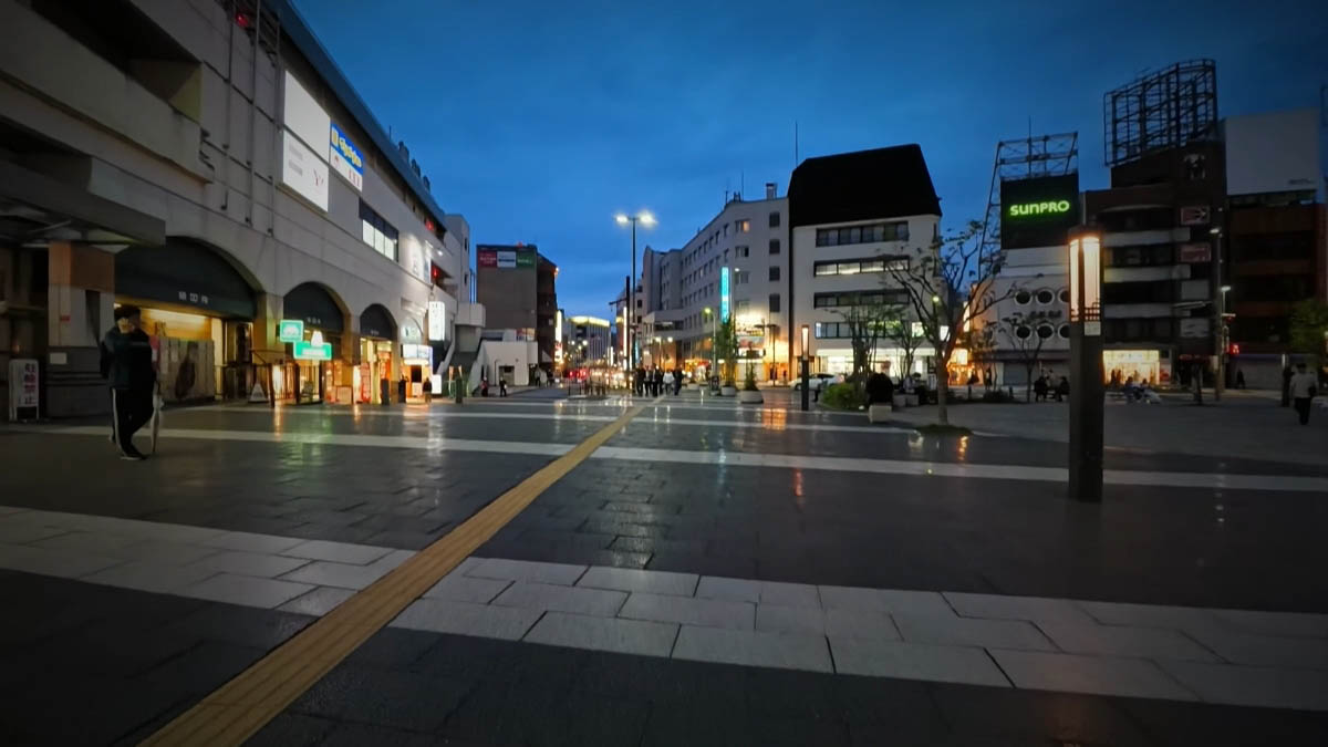 The plaza in front of Oshiroguchi at night, with arched openings, streetlamps, and a green SUNPRO sign