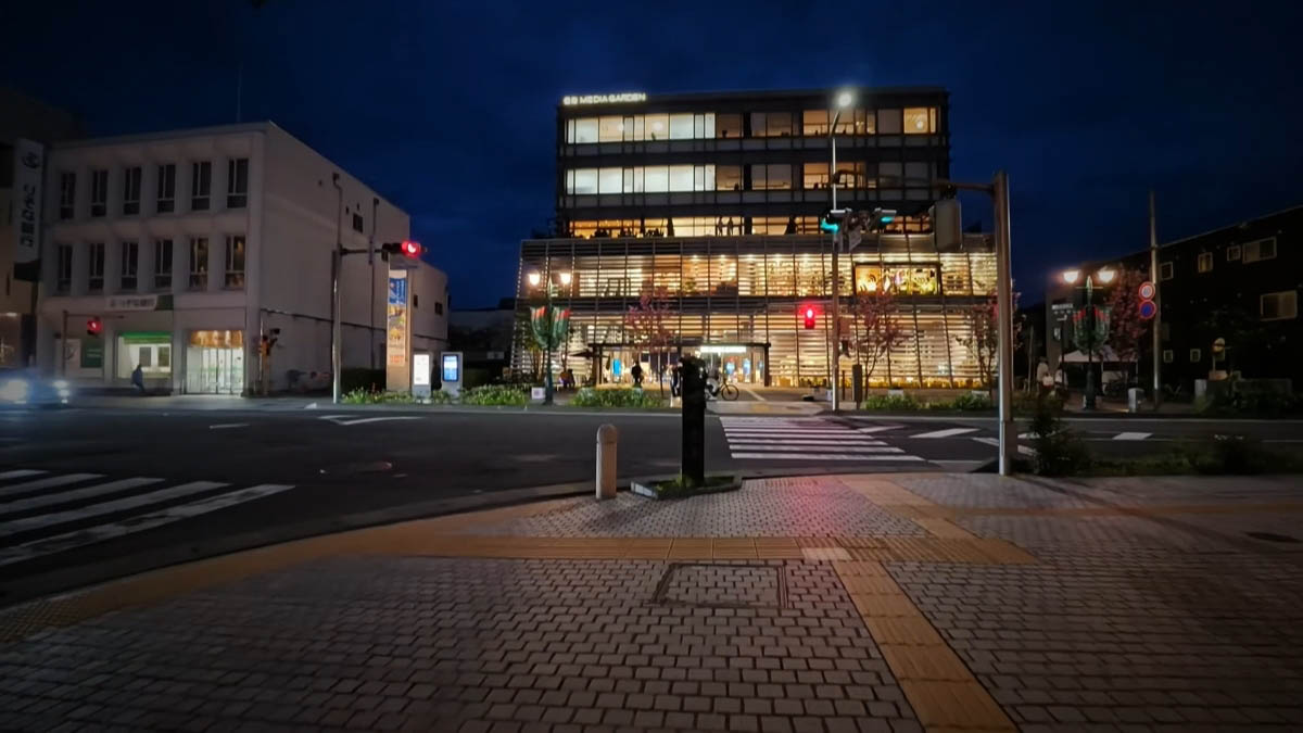 Shinmai MEDIA GARDEN and Hachijuni Bank across a crosswalk, with tactile paving in the foreground