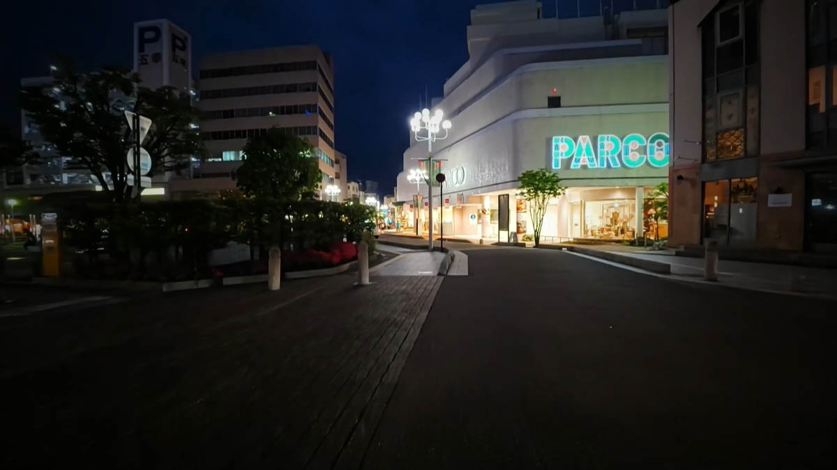 PARCO at night, with teal neon and white streetlamps