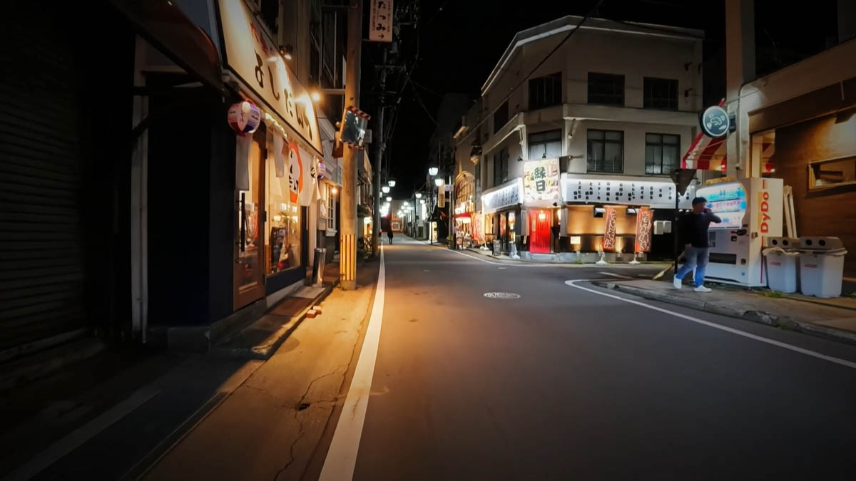 よしだと縁日 よしだの看板と縁日の赤い扉。自動販売機の前に立つ人