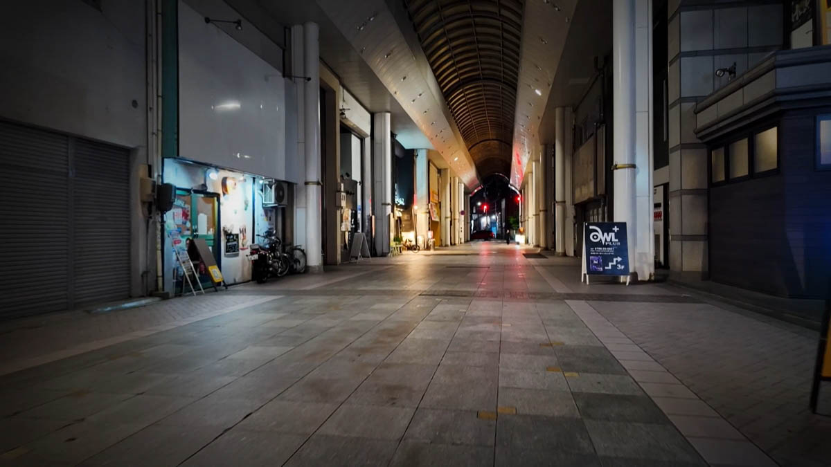 owl PLUS owl PLUS sandwich board and white arcade pillars; red traffic light ahead