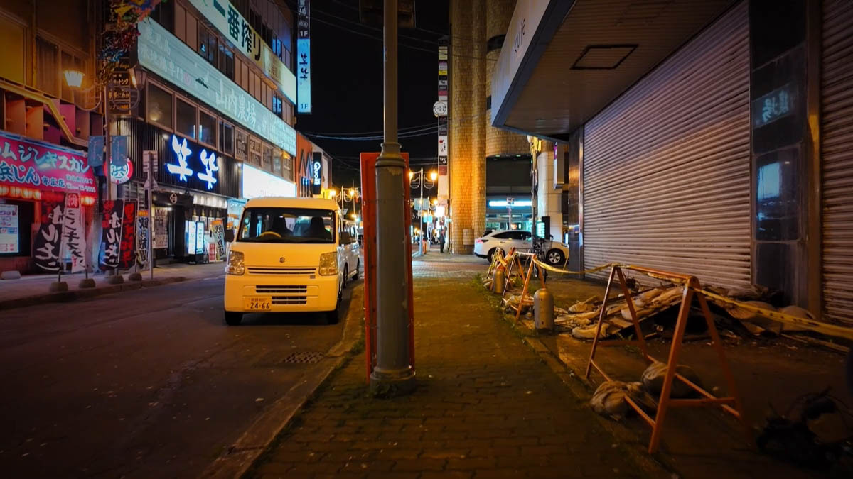 Wara-wara and Yamauchi Nojo signs with a white kei van and orange barriers