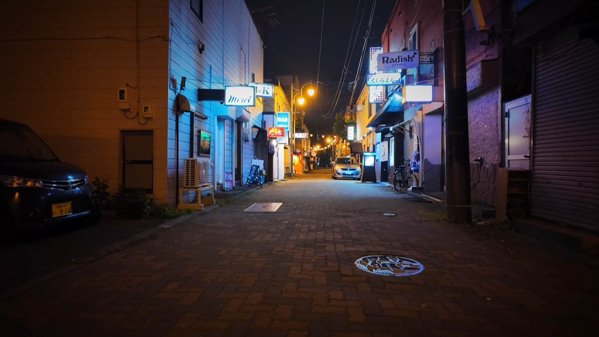 Narrow alley with Merci and Radish neon signs
