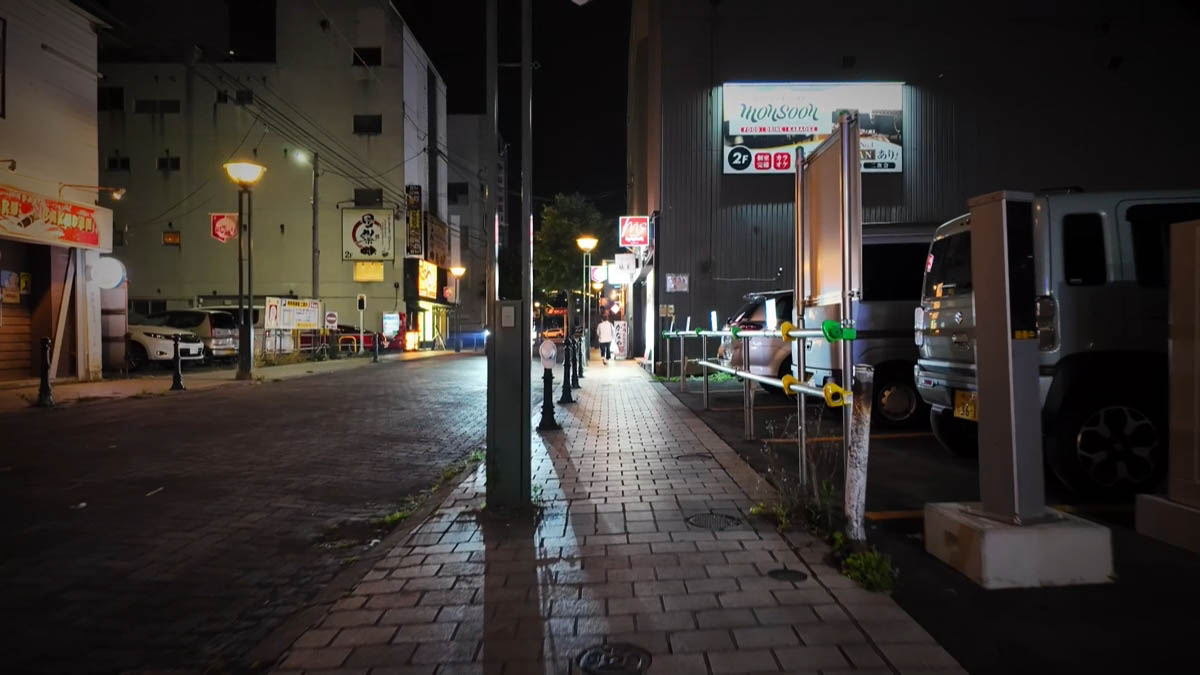 Monsoon Monsoonの看板と、歩道を歩く一人の人