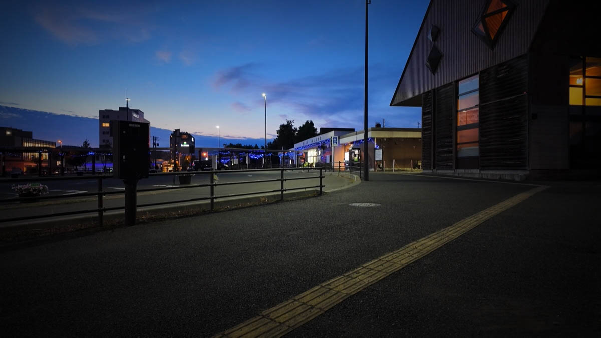 夕暮れの駅前。覆いのある歩道に青い電飾が続く