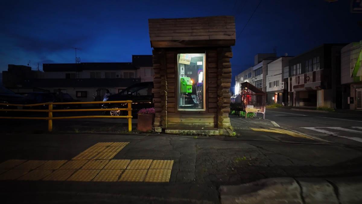 丸太の小屋の中で光る緑色の公衆電話