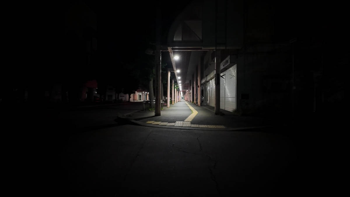 Covered sidewalk with closed shutters and a line of tactile paving