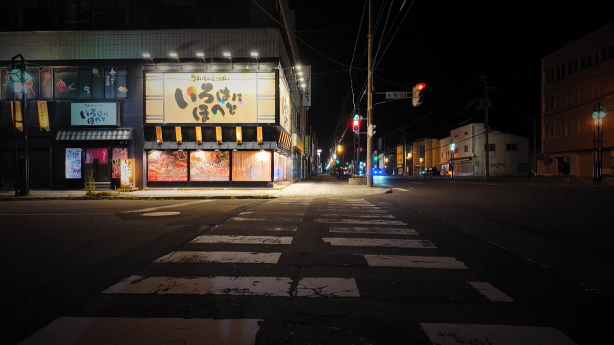 Large Irohanihoheto sign and a dark street beyond