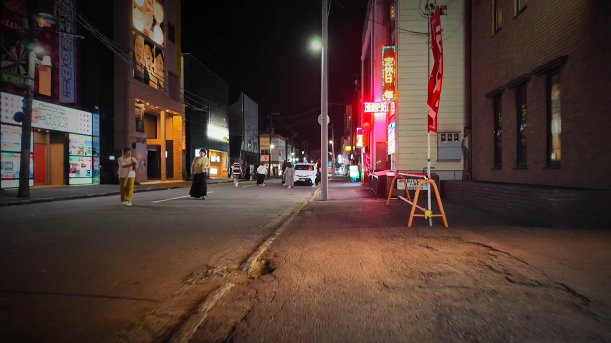 Mahjong neon and walkers farther down the street