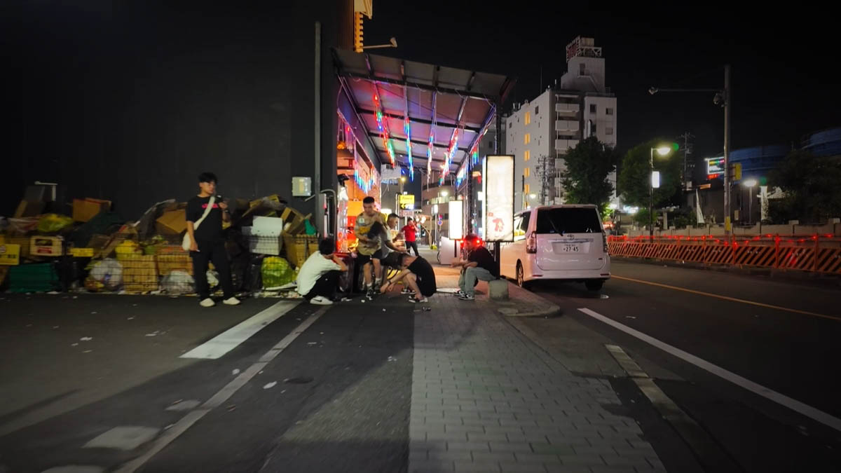 Van and cardboard Cardboard stacks, a white van, and people crouched under lights