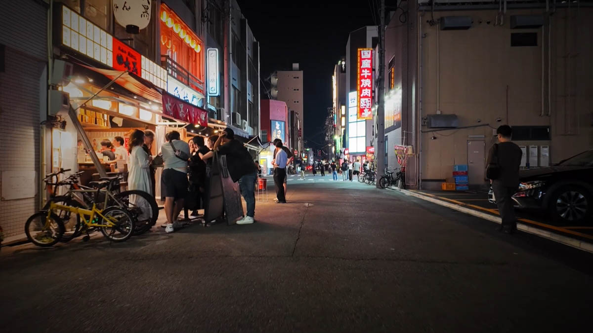 Stall street Crowd at a food stall, yakiniku sign farther down