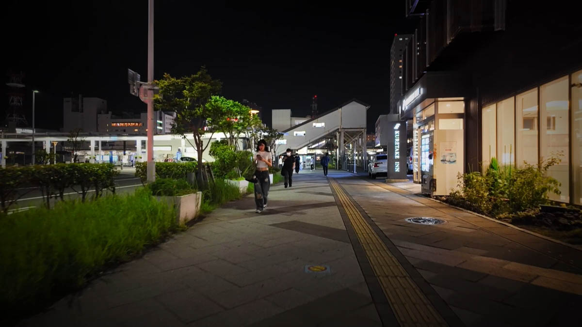 くれたけイン前 くれたけインの看板と、スマホを見る女性